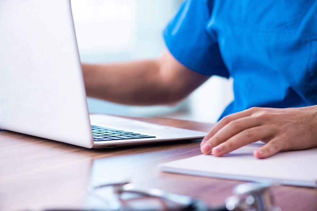 closeup of a nurse working on a laptop - only their hands and laptop are visible