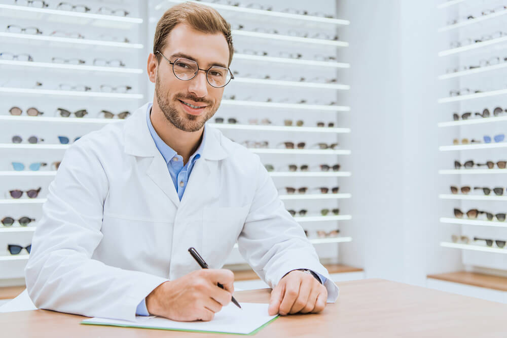 smiling eye doctor in glasses writing a note